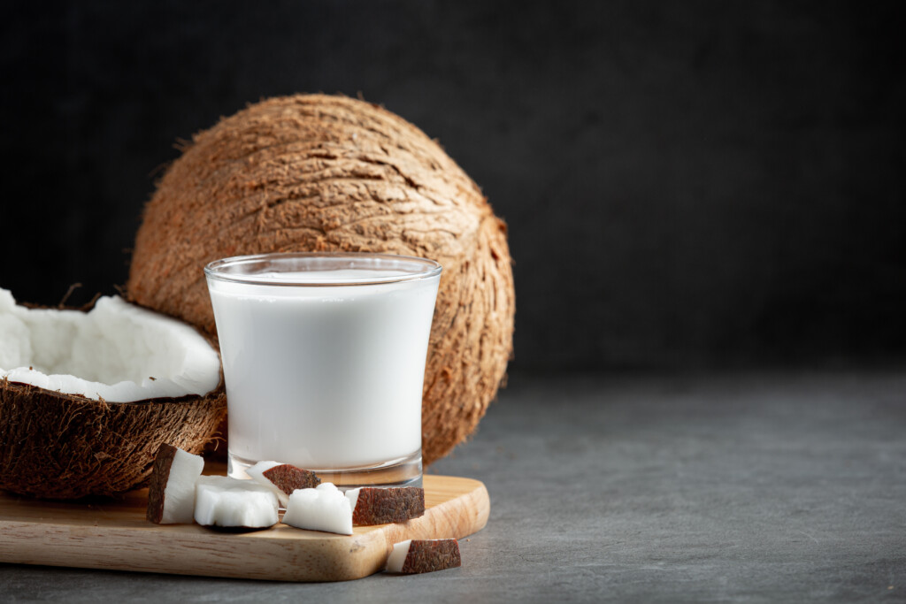 a glass of coconut milk put on wooden cutting board