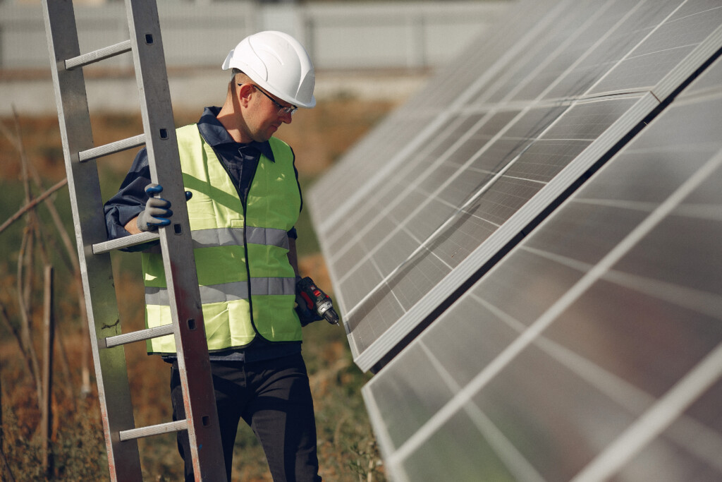 Engineer in a white helmet. Man near solar panel. Worker with a ladder