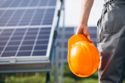 Man worker in the firld by the solar panels