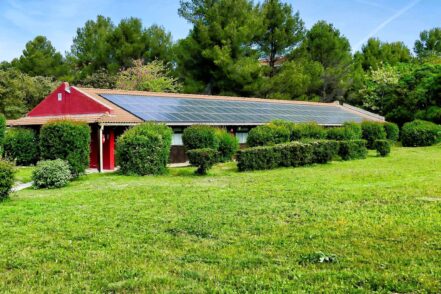 A vertical shot of a small house with solar panels in the green field in the Canary Islands