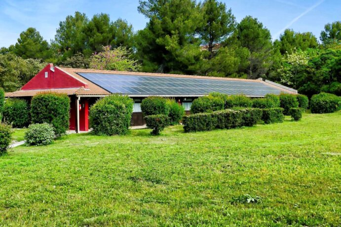 A vertical shot of a small house with solar panels in the green field in the Canary Islands