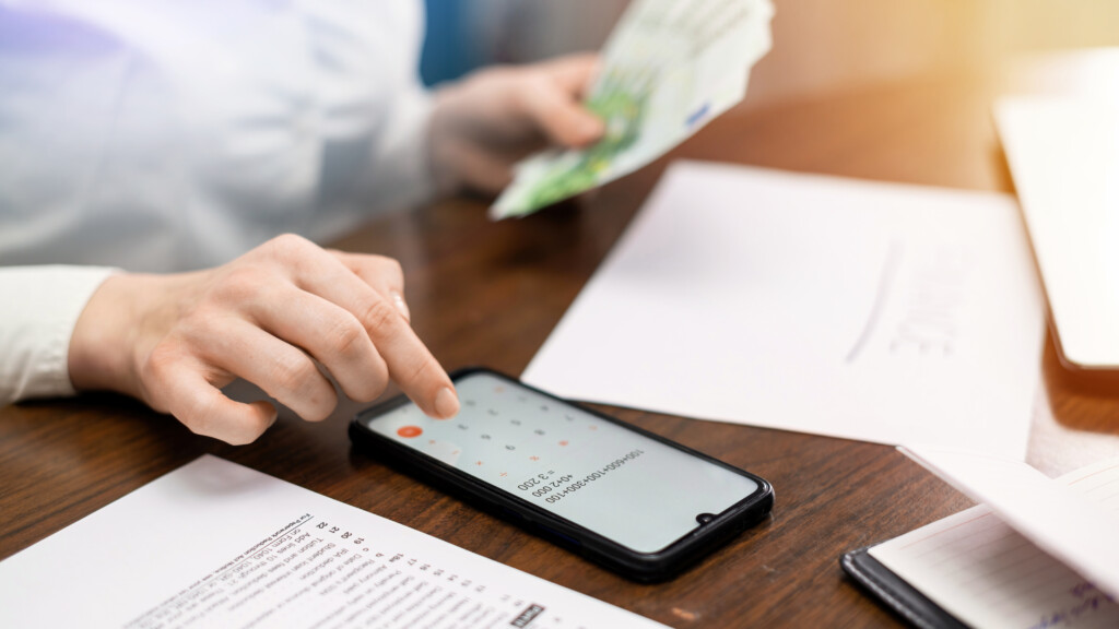 Woman working with finances on the table. Smartphone, money, notepad